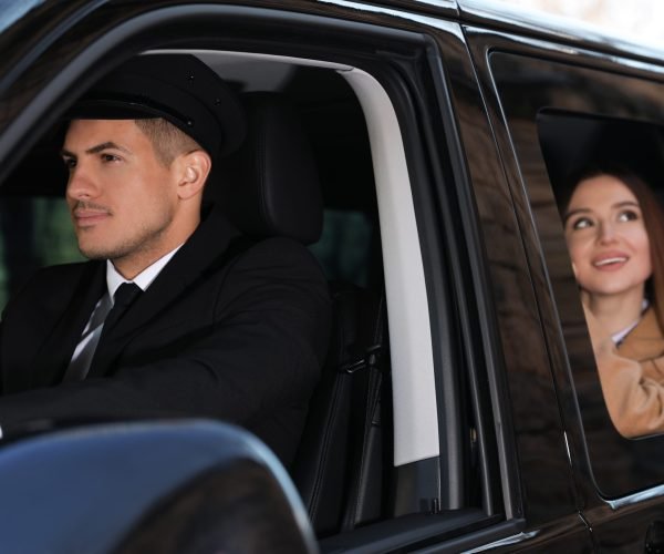 Professional driver and businesswoman in luxury car. Chauffeur service